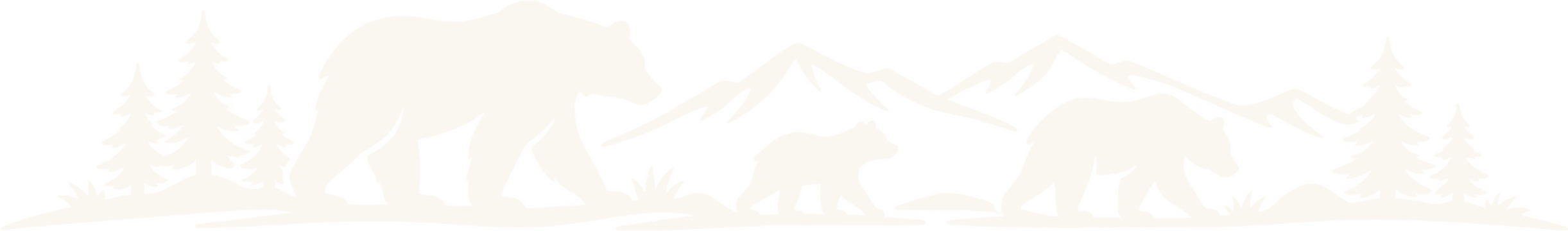 A bear and two cubs walking below a mountain range and pines